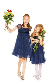 Two charming little girls in a blue dresses with a bouquet of flowers