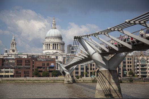 View on St Paul's Cathedral at the distance and Millennium bridge over Thames River. People on the bridge. 
