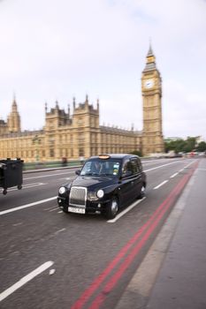 Typical London taxi in front of a Big Ben. Other traffic in the background.