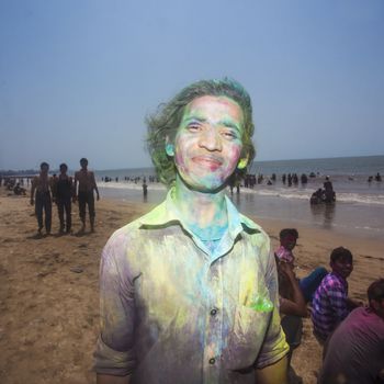Portrait of young Indian man celebrating Holi on Juhu Beach in Mumbai.