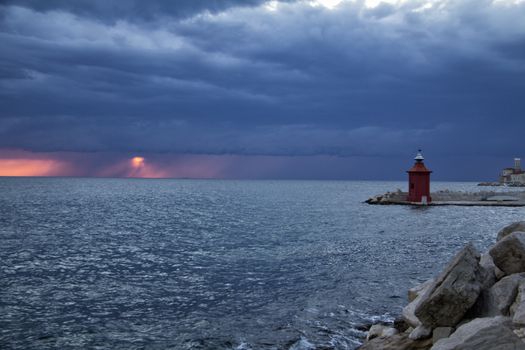 Amazing sunset over sea and cloudy sky, with lighthouse shot in Piran, Slovenia.