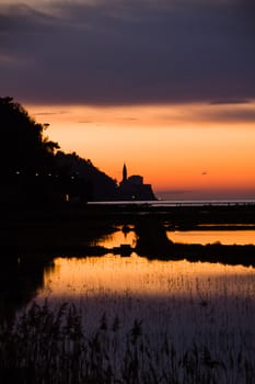 Sunset on saltpans with a church in the back (in Strunjan/Piran, Slovenia)