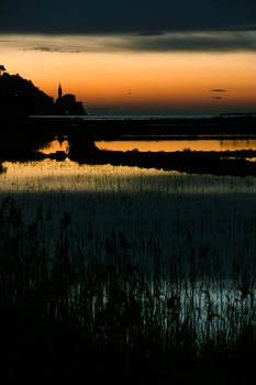 Sunset on saltpans with a church in the back (in Strunjan/Piran, Slovenia)