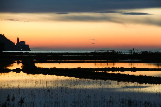 Sunset on saltpans with a church in the back (in Strunjan/Piran, Slovenia)