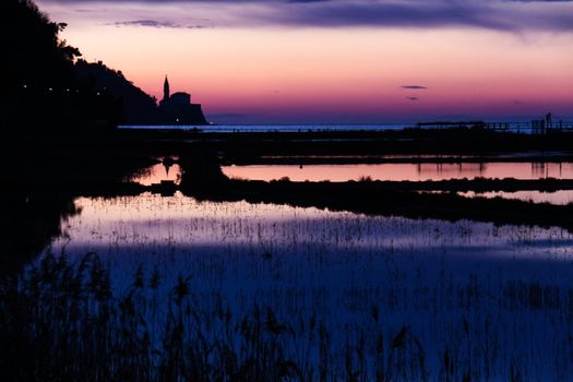 Sunset on saltpans with a church in the back (in Strunjan/Piran, Slovenia)