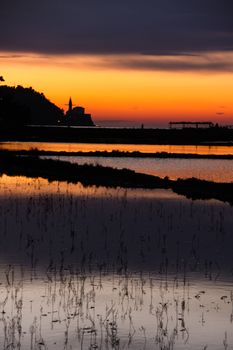 Sunset on saltpans with a church in the back (in Strunjan/Piran, Slovenia)