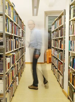 PULA, CROATIA - JANUARY 28, 2016: Unidentified man standing and reading book in library in Pula on January 28, 2016        