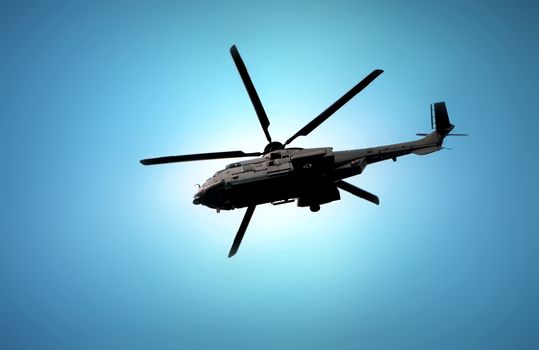 Military helicopter flying under blue sky