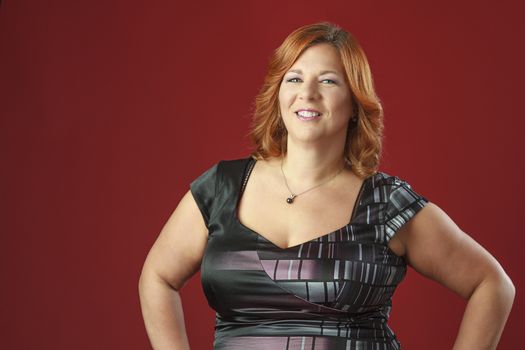 Woman in her fortie, wearing a cocktail dress, against a red background