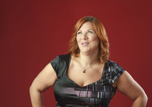 red hair woman in cocktail dress against a red background, craking up 