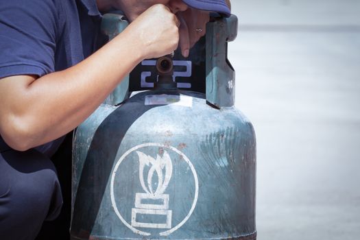 Cigarette in hand near gas tank cylinder can ignition of flammable, safety concept