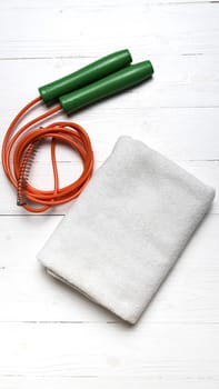 fitness equipment:white towel,jumping rope on white wood table