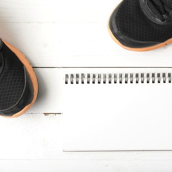 running shoes and notepad on white wood table