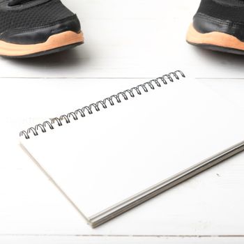 running shoes and notepad on white wood table