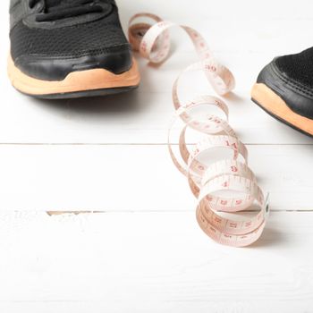 running shoes and measuring tape on white wood table