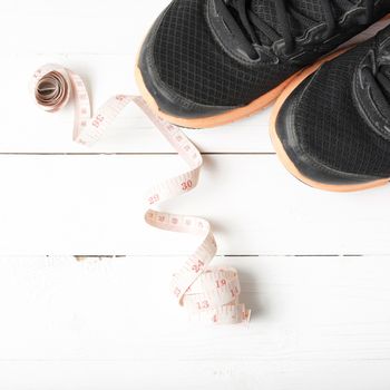 running shoes and measuring tape on white wood table