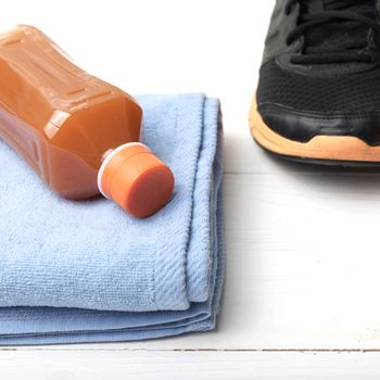 running shoes,towel and orange juice on white wood table