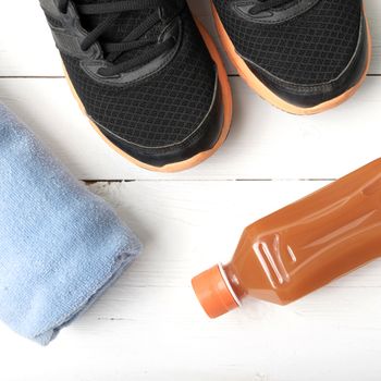 running shoes,towel and orange juice on white wood table