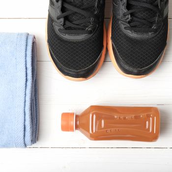 running shoes,towel and orange juice on white wood table