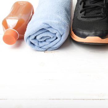 running shoes,towel and orange juice on white wood table