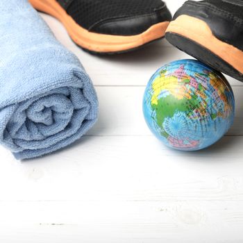 running shoes,towel and earth ball on white wood table concept world healthy