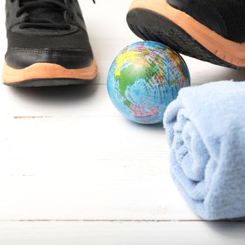 running shoes,towel and earth ball on white wood table concept world healthy