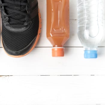 running shoes,drinking water and orange juice on white wood table