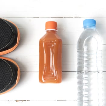 running shoes,drinking water and orange juice on white wood table