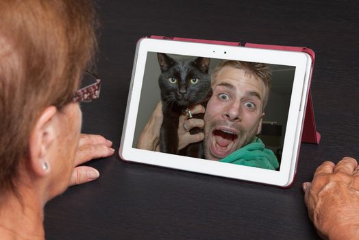 Senior woman with tablet contacting her family