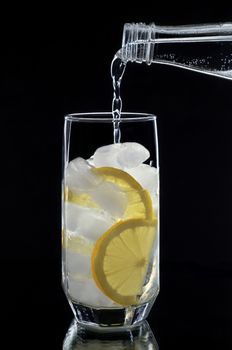 Water is poured from the bottle, ice and lemon slices