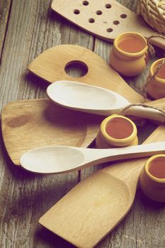 Arrangement of Wooden Kitchen Utensils with  Spoons, Spatula and Small Pots closeup on Rustic Wooden background. Retro Styled