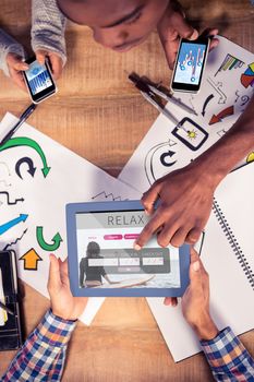 Overhead view of creative team working at desk against holidays booking app