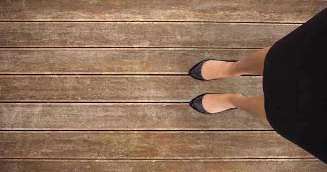 Businesswomans feet against wooden planks background