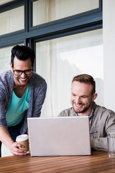 Happy gay couple using laptop outdoors