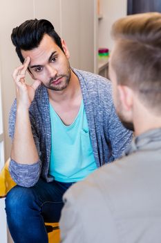 Thoughtful gay couple talking at home