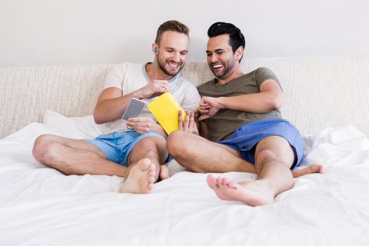 Happy gay couple reading book in bed