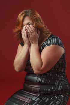 woman on her knees hidding her laugh inside her hands