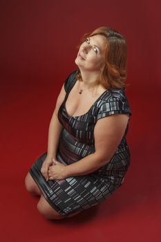 Woman in her fortie, wearing a cocktail dress, sitting on her knees