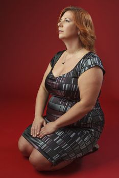 Portait of a woman on her knees against a red background