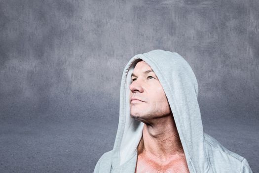 Thoughtful man looking up against grey wall