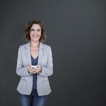 Portrait of smiling businesswoman using mobile phone against grey background
