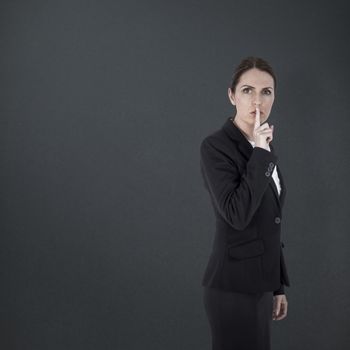 Businesswoman asking for silence over white background against grey background