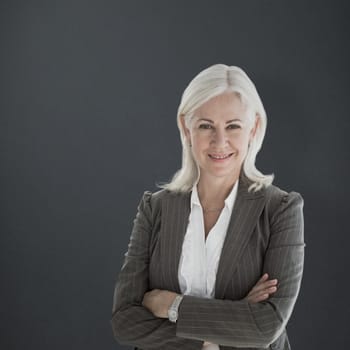 Portrait of happy businesswoman with arms crossed against grey background
