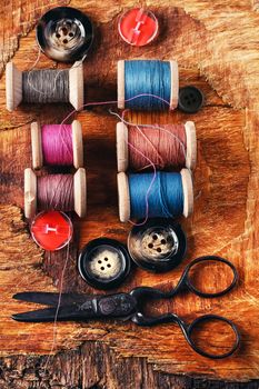 Six antiquated sewing thread and buttons on retro background