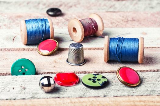 spools of thread and various buttons on wooden background