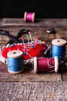 pin cushion with needles,thread and buttons for sewing on stylish wooden background