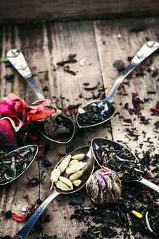Spoon and spilling the tea leaves of different varieties on retro background