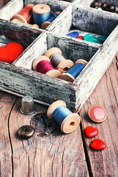 Wooden box with reels of sewing threads and buttons