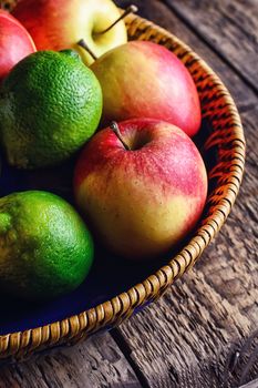 Harvest ripe apples and lime in stylish dish on wooden background