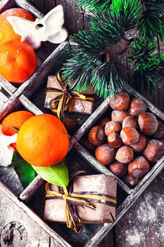 Decorative wooden box with hazelnuts,mandarins and gifts.